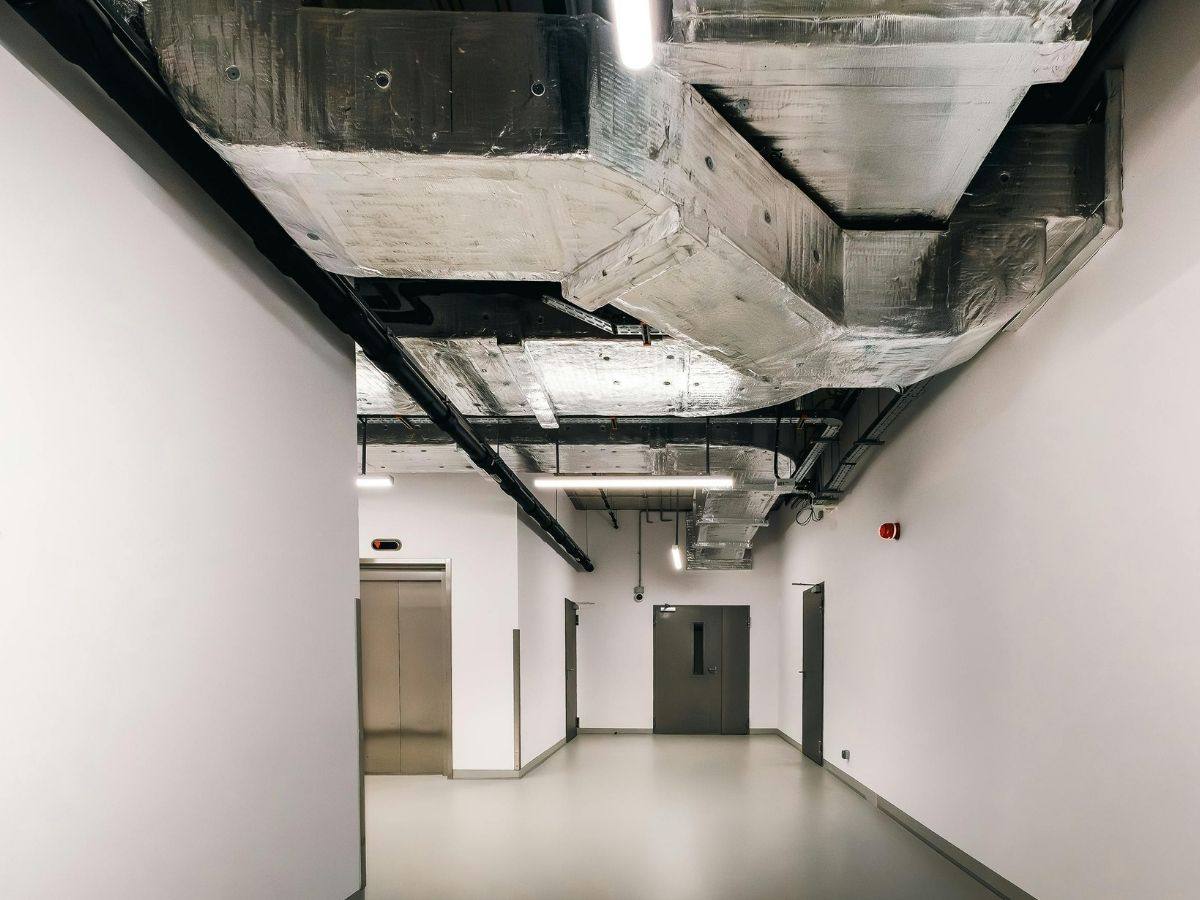 Insulated ductwork running along the ceiling of a commercial corridor