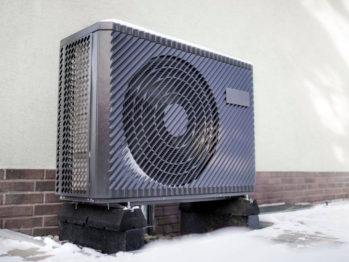 Cold climate heat pump installed outside a home in winter snow