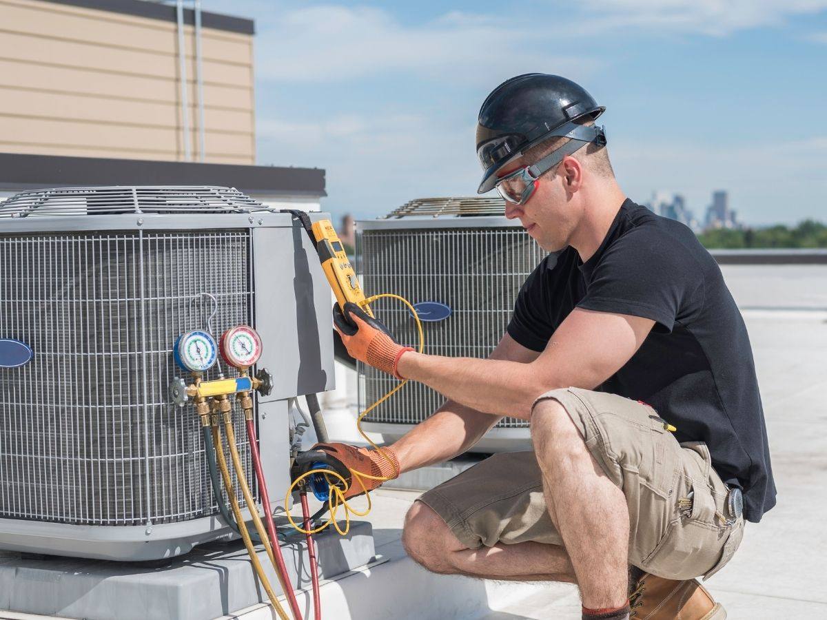 HVAC technician inspecting a rooftop air conditioning condenser